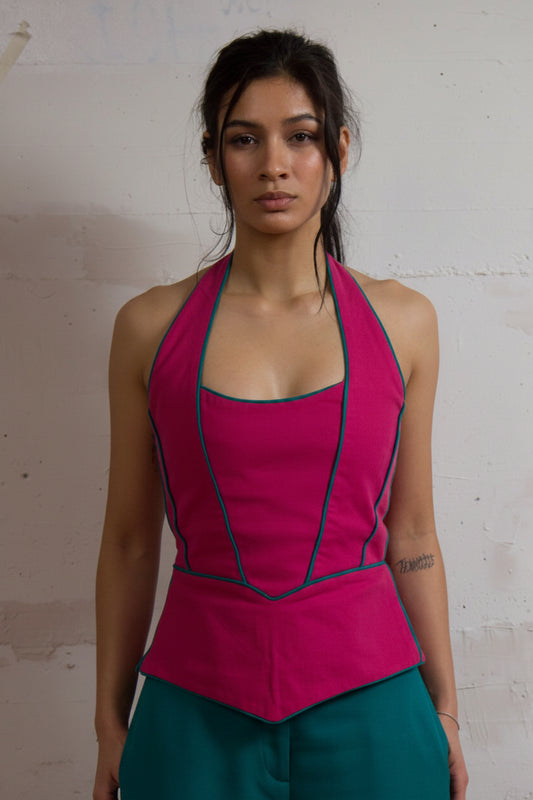 A model wearing a pink halterneck top with a keyhole back and turquoise green patchwork trousers.